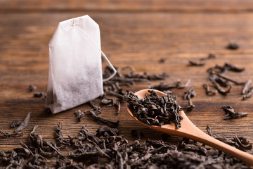 Tea bag on wooden background. Tea bag and tea leaves with a spoon on a wooden background.