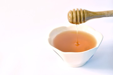 honey on wooden scoop drop to cup in white background