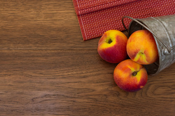 Bucket of peaches over wooden background with copy space 
