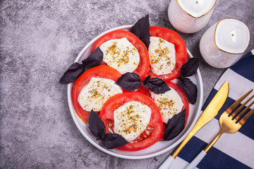 traditional Italian caprese salad, snack of tomato, mozzarella cheese, basil and spices, top view, copy space