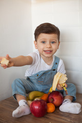Fototapeta premium Boy with fruits and vegetables in kitchen