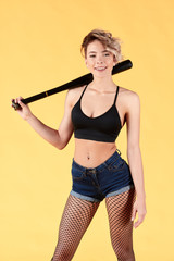 positive cute fair-haired woman holding baseball bat or racket isolated yellow background. studio shot. close up portrait.