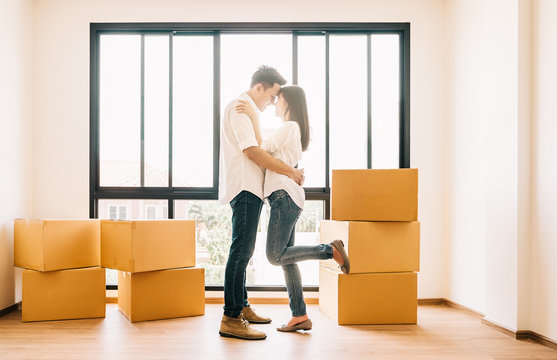 Asian couple embracing in their new home - Powered by Adobe