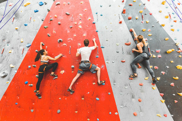 Athletes climber moving up on steep rock, climbing on artificial wall indoors. Extreme sports and...