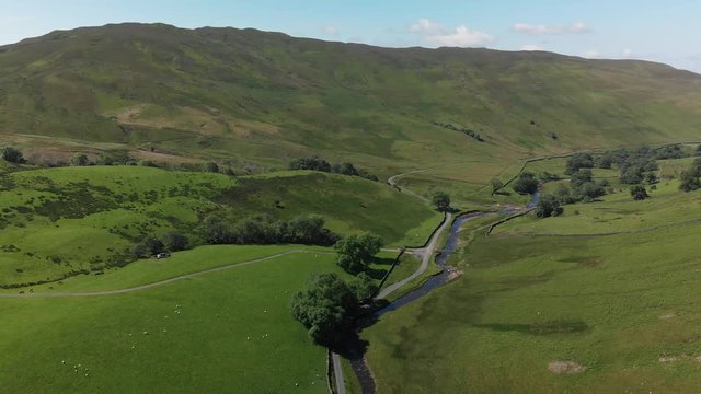 A static aerial shot of Barbon Beck, Carnforth, Lancashire, England. This stunning countryside features a stream running alongside a small country lane.