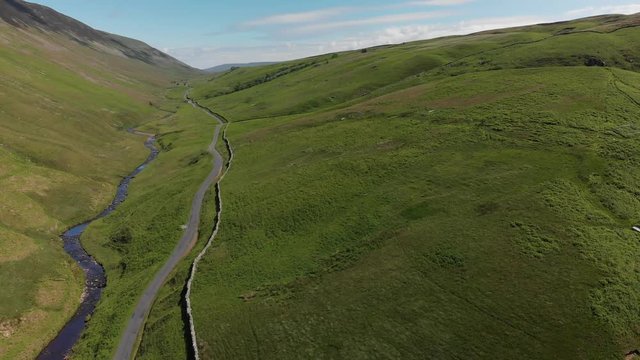 An aerial shot of Barbon Beck, Carnforth, Lancashire, England. This stunning countryside features a stream running alongside a small country lane.