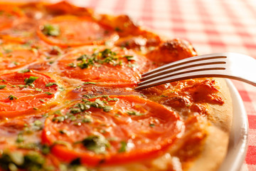 Close up eating piece of pizza with a fork, Pizza Margarita. Delicious hot food sliced and served on white platter. Menu photo, Italian fast food.
