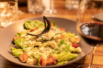 Fresh caesar salad in brown plate on dark wooden table with Shallow depth of focus over dark grunge background