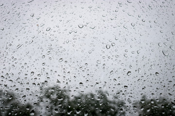 Large drops of water on the glass. Raindrops on the windshield of a car against the background of the sky sky.