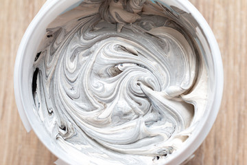 textured putting mixed with black paint in a round plastic container