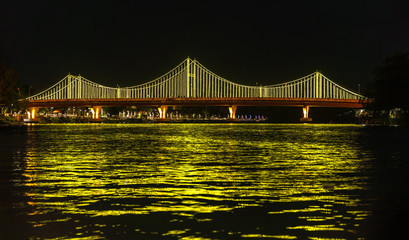 Fototapeta premium The city lights of Surat Thani at twilight with the Bridge and reflection over the Tapee River in Surat Thani , Thailand