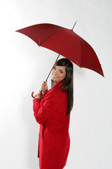 Jeune femme brune souriante sous un parapluie rouge