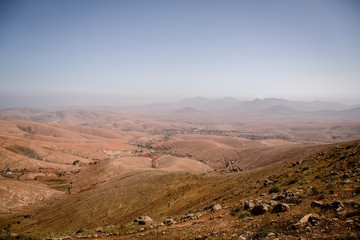 Typical landscape with red volcanic mountains and a small village close to betancuria on the Canary Island Fuerteventura, Spain.