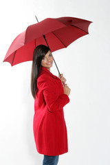 Jeune femme brune souriante sous un parapluie rouge