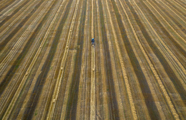 tractor, agricultural machinery collects straw in sheaves, view from the quadcopter
