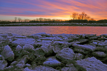 The Grand River at sunrise with ice chunks on the banks. Shot during early spring in Waterloo,...