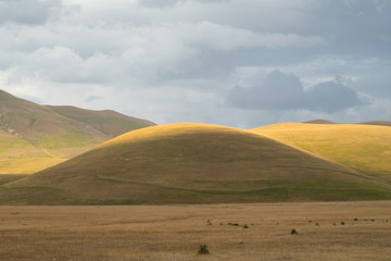 Natural landscape of the plain of Castelluccio di Norcia in the warm light of the sunset. Apennines, Umbria, Italy