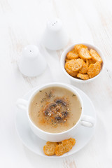 delicious mushroom cream soup with croutons on white table, vertical, top view