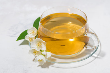 glass cup with green tea on a white background and jasmine, closeup top view
