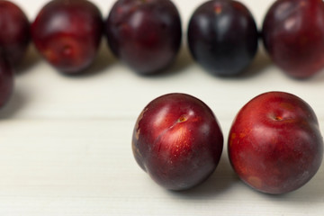 Ripe plums on a wooden background close-up. Open space, healthy food concept, plants, soil, organic natural products, natural food, vegetarian dishes, vegetables, raw, food festival