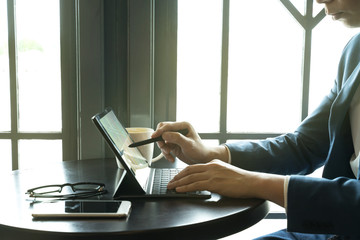 businessman point the stylus pen to tablet for analysis graph visualization at coffee shop