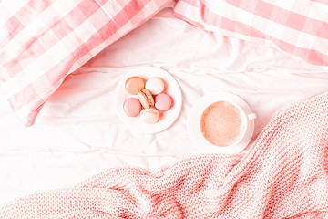 Obraz na płótnie Canvas Bed with pink knitted plaid, coffee and macaroons.