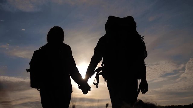 happy family tourists walking holding hand silhouette at sunset . hikers teamwork travel concept. man lifestyle and woman couple with backpacks tourists adventure evening tour at sunset