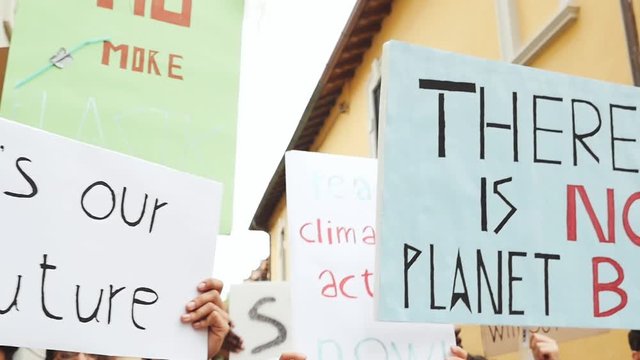 Public demonstration on the street against global warming and pollution. Group of multiethnic people making protest about climate change and plastic problems in the oceans