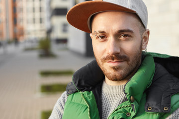 Close up portrait of handsome charismatic guy with brown eyes, bristle and pierced earrings waiting...