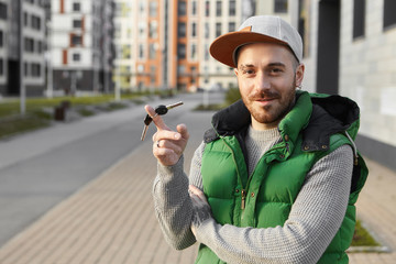 Outdoor summer picture of overjoyed handsome young bearded man having cheerful confident facial...