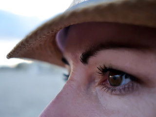 Brown eyes of a young woman in a hat looking to the side, close-up