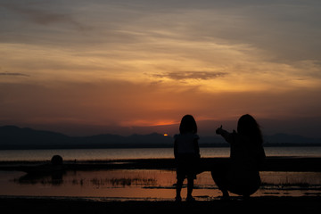 Fototapeta na wymiar Silhouette of mother and daughter on sunset,Thailand people,Happy family concept,Mother day concept