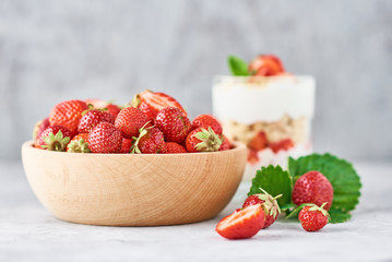 Strawberry granola or smoothie in glass and fresh berries in a wooden bowl. Healthy breakfast