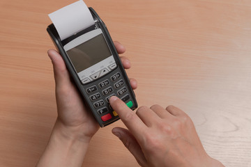 A person holds in his hand a terminal for paying for purchases in a store using bank cards or NFC
