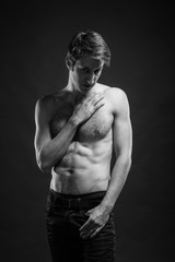 Naklejka premium Full length portrait of a sexy young man in jeans and shirtless posing at studio.