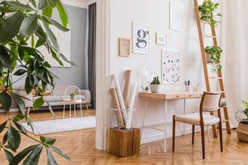Modern and design home interior of open space with wooden desk, sofa, chair, cube, a lot of plants, mock up poster frames and elegant accessories. Stylish and minimalistic home decor. Template.