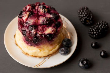 Delicious cottage cheese casserole with berries, cottage cheese pudding with berries. Appetizing fresh cottage cheese casserole with blueberries, currant and blackberries on a dark gray background.