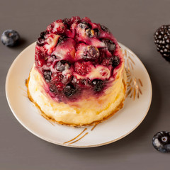 Delicious cottage cheese casserole with berries, cottage cheese pudding with berries. Appetizing fresh cottage cheese casserole with blueberries and blackberries on a dark gray background.