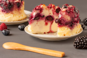 Delicious cottage cheese casserole with berries, cottage cheese pudding with berries. Appetizing fresh cottage cheese casserole with blueberries, currant  and blackberries on a  gray background.