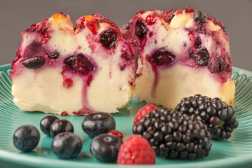 Delicious cottage cheese casserole with berries, cottage cheese pudding with berries. Appetizing fresh cottage cheese casserole with blueberries and blackberries on a dark gray background.