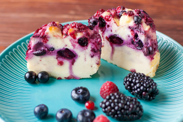 Delicious cottage cheese casserole with berries, cottage cheese pudding with berries. Appetizing fresh cottage cheese casserole with blueberries, raspberries, blueberries and blackberries on a table
