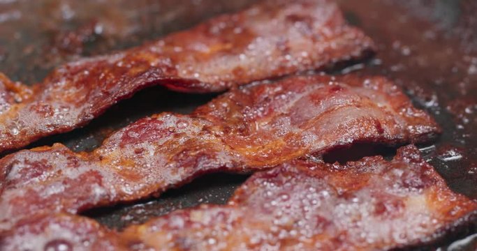 Fry bacon in pan in kitchen for breakfast