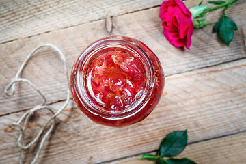 Jar of rose petal jam on a wooden table. Homemade jam of rose petals.