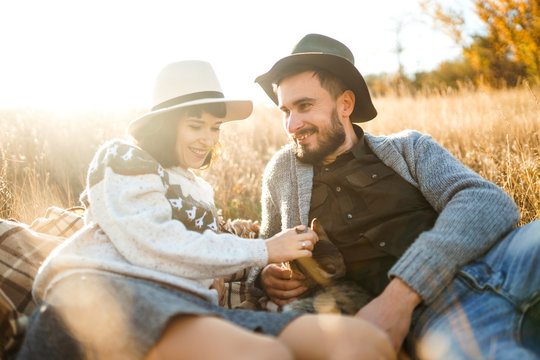 Lovely hipster couple with cat. Couple wearing beautiful hats and sweaters. Lifestyle, happy couple of two play on a sunny day in the park. The concept of youth, love and lifestyle. Sunset in autumn.