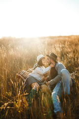 Lovely hipster couple with cat. Couple wearing beautiful hats and sweaters. Lifestyle, happy couple of two play on a sunny day in the park. The concept of youth, love and lifestyle. Sunset in autumn.