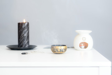 Cozy home interior decor, burning candles. Burning candles on wooden white table against grey wall. Space for text. Soft focus.