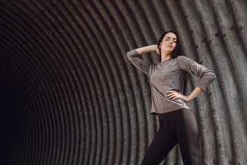 Sports woman posing in fashion sportswear on tunnel urban gray background. Fitness model working out outdoor.