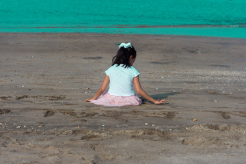 lonely girl child playing in the beach beside the sea during summer holidays