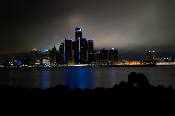 Silhouette of a couple watching Detroit skyline at night