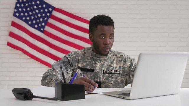 American soldier in uniform working with laptop in office